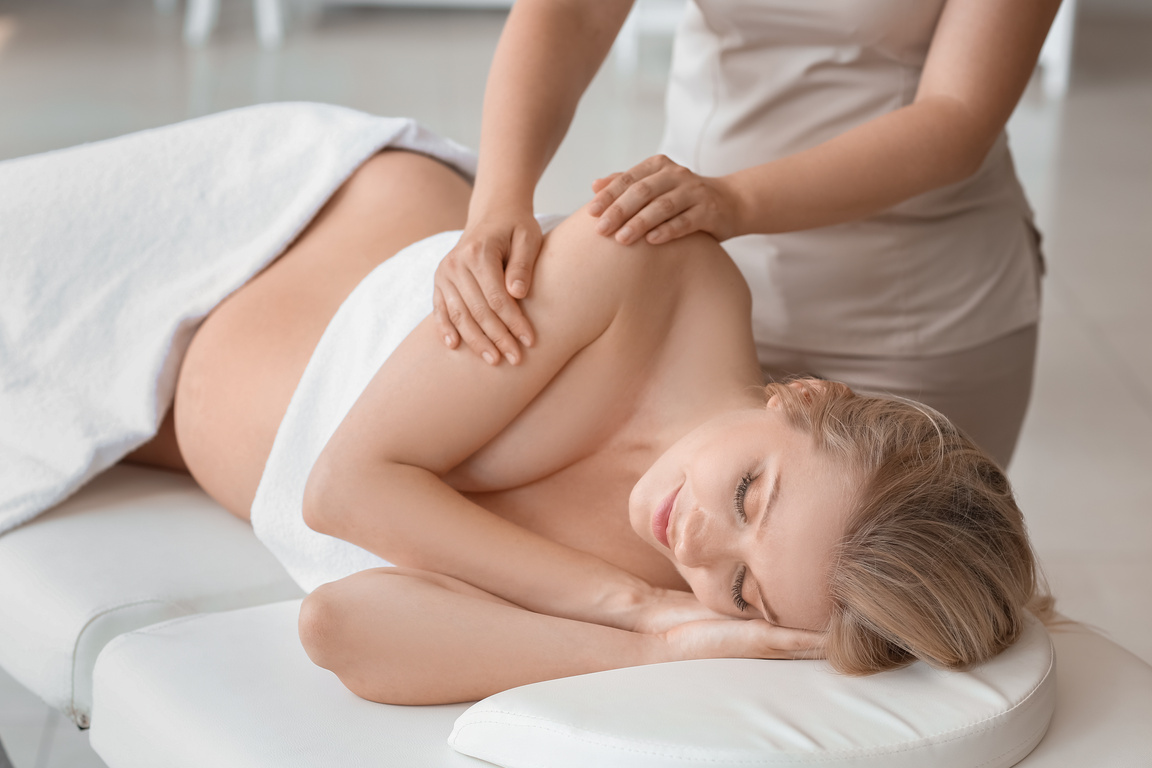 Young Pregnant Woman Having Massage in Spa Salon